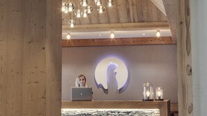 Un mostrador de recepción con una computadora portátil, techo de madera y una pared con una lámpara.