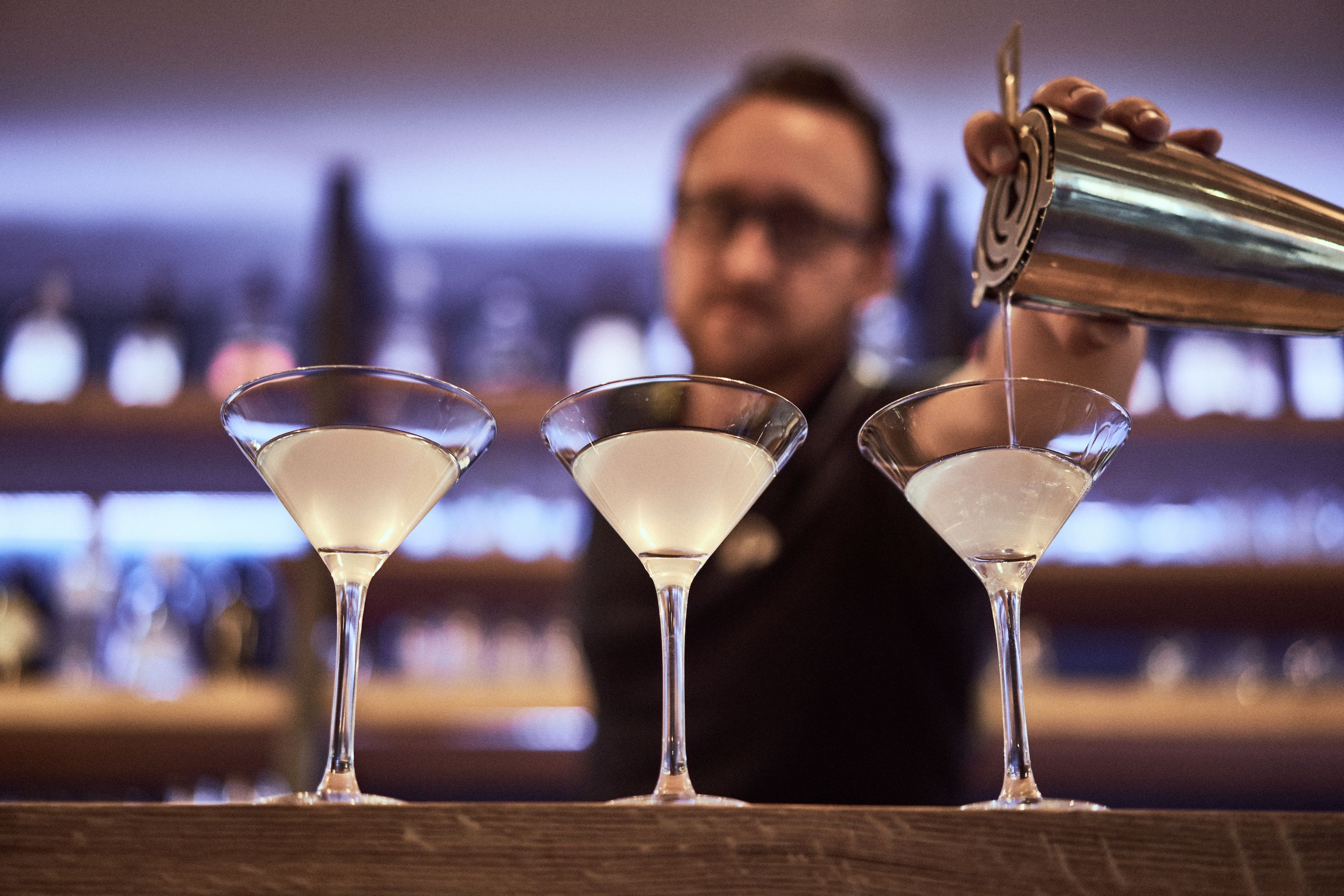 Un barman verse une boisson dans un verre à martini.