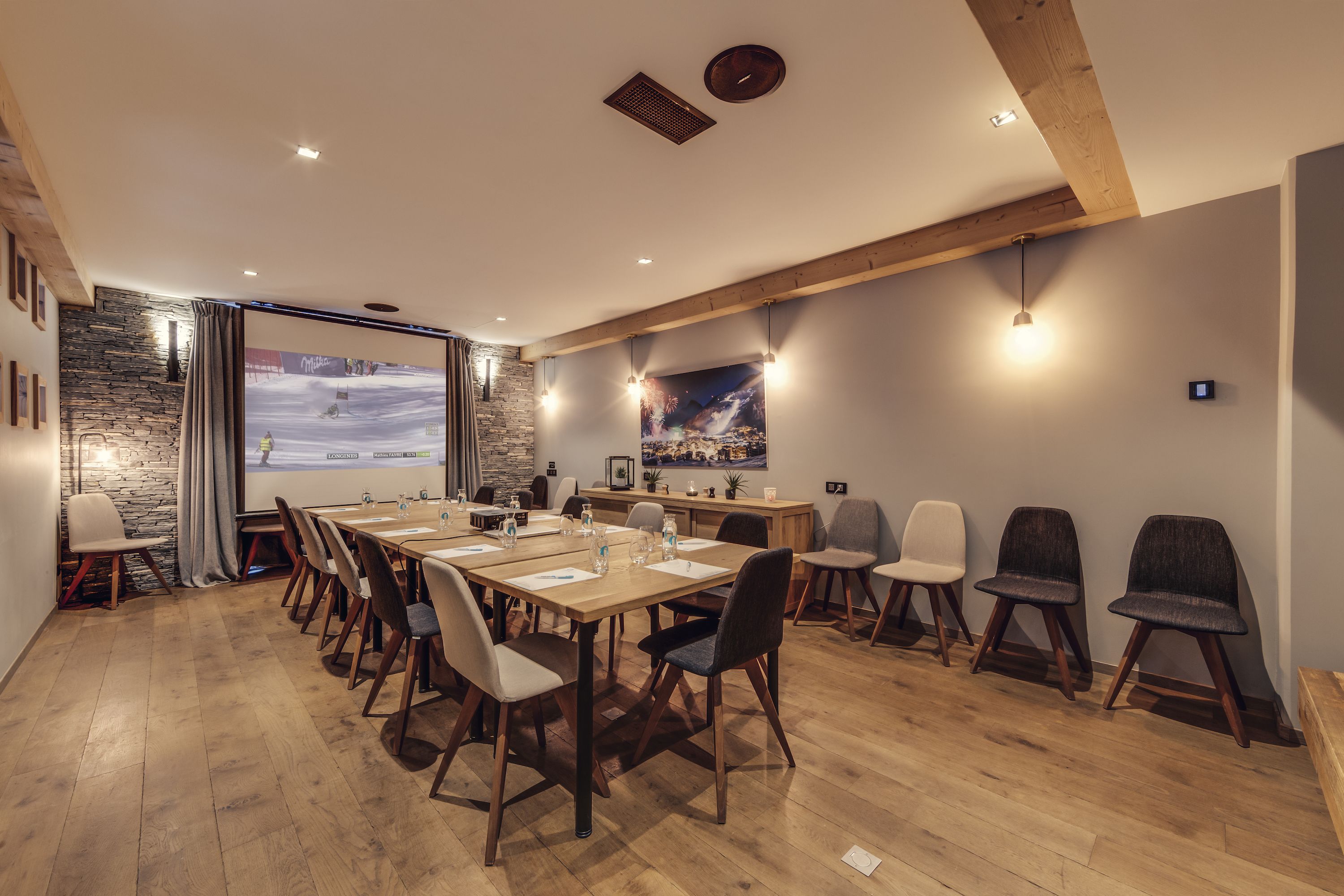 A conference room with a long table, chairs, a stone wall, and a large window with a view.