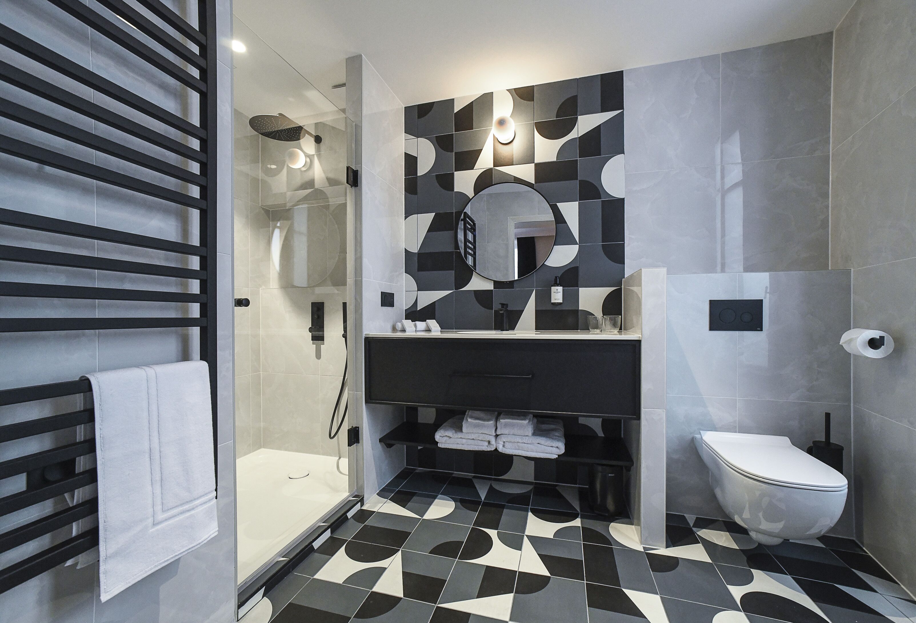 A modern bathroom with a shower, a toilet, and a sink with a mirror.