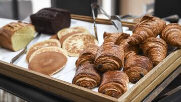 Un plateau contenant un assortiment de produits de boulangerie, notamment des croissants, une miche de pain et des crêpes.