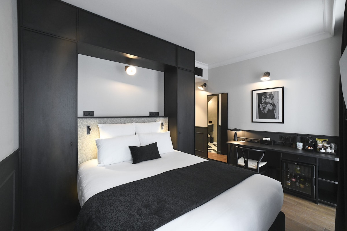 Een moderne hotelkamer met een groot bed, een bureau en een kleine kitchenette.