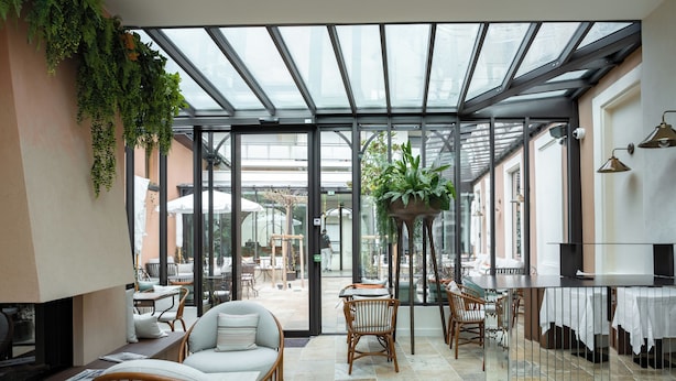 Un espace intérieur moderne doté d’un plafond en verre, de coins salon et d’une plante centrale.