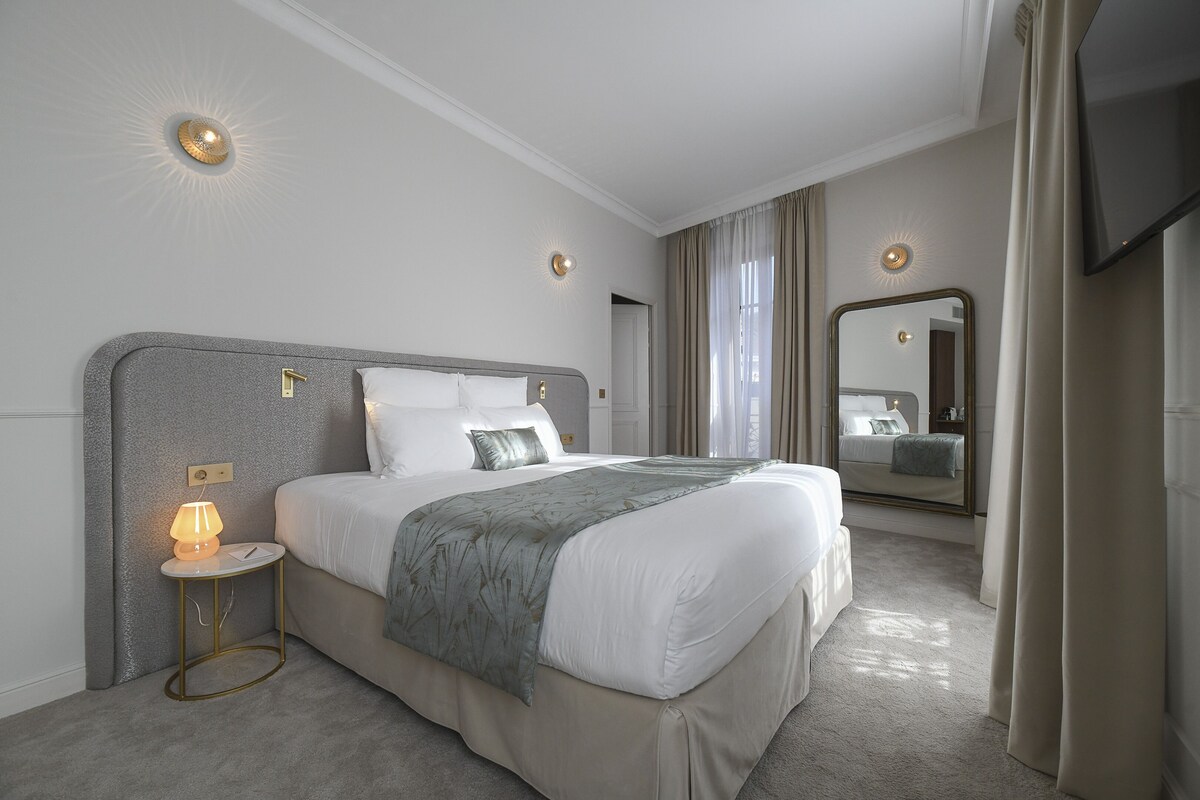 Een moderne hotelkamer met een groot bed, een bedlampje en een flatscreen televisie.