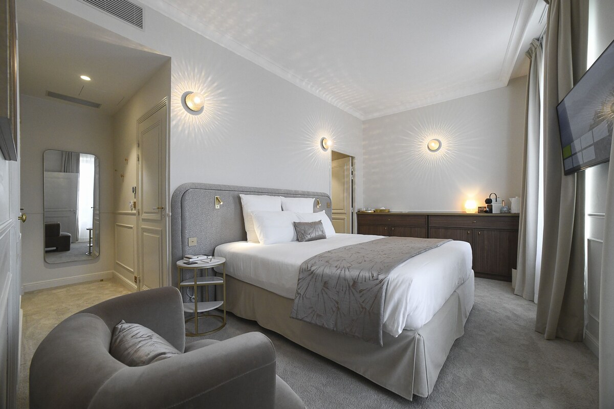 Een moderne hotelkamer met een groot bed, een zithoek, een kaptafel en een televisie.