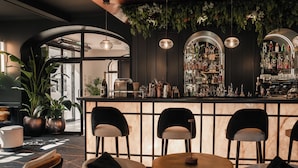 Un espace bar comprenant un comptoir, des tabourets de bar et un coin salon avec des tables et des chaises rondes.