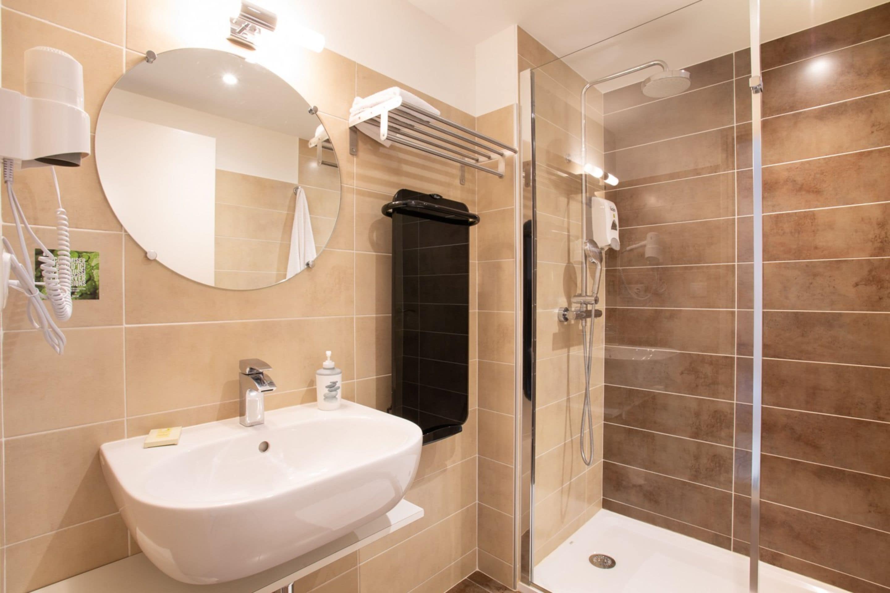 Baño con lavamanos, espejo, toallero y ducha.