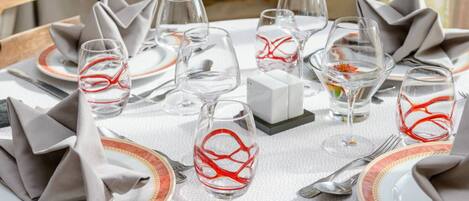 Una mesa lista para una comida, con platos, vasos y cubiertos.