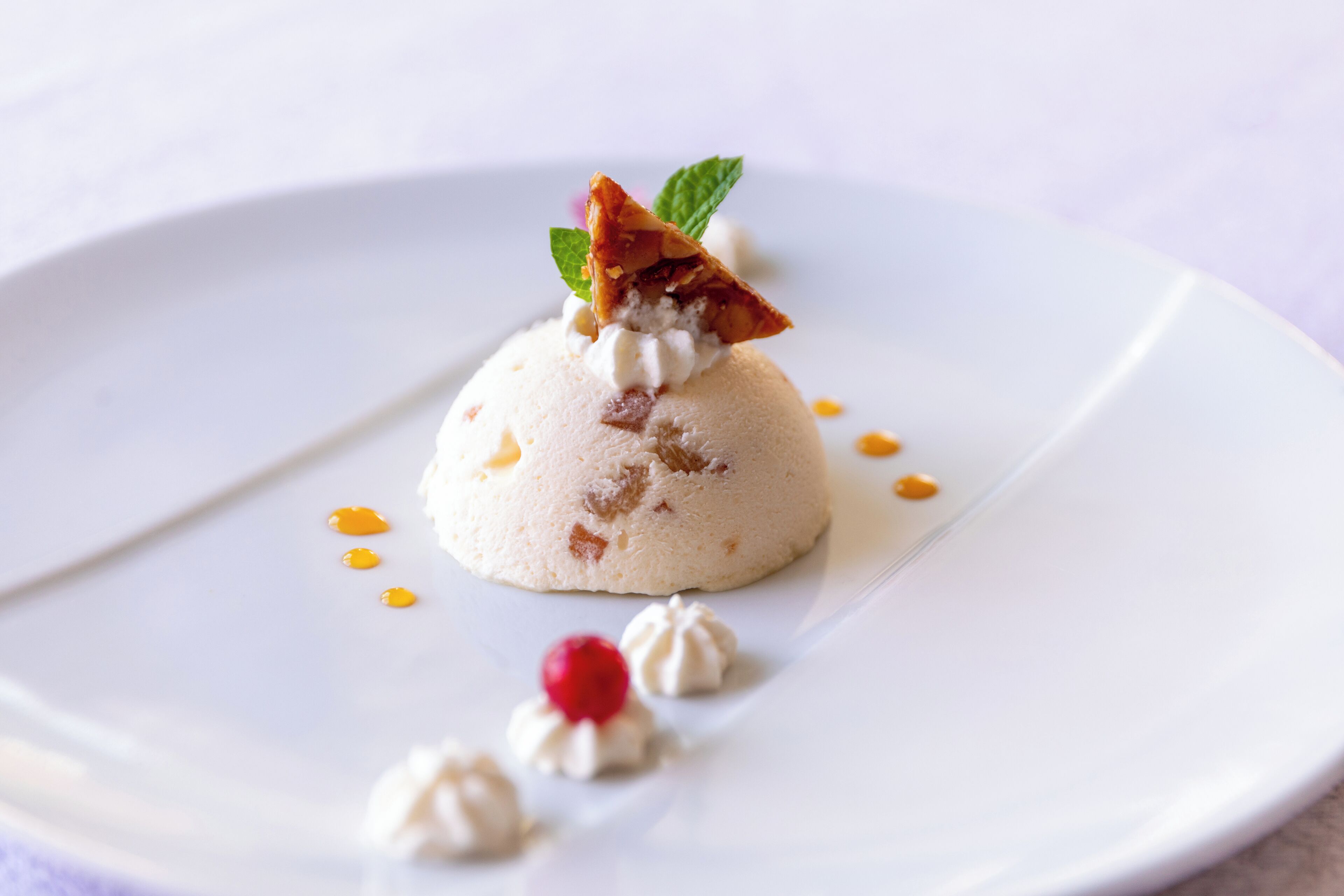 A dessert on a white plate with a mint leaf garnish.
