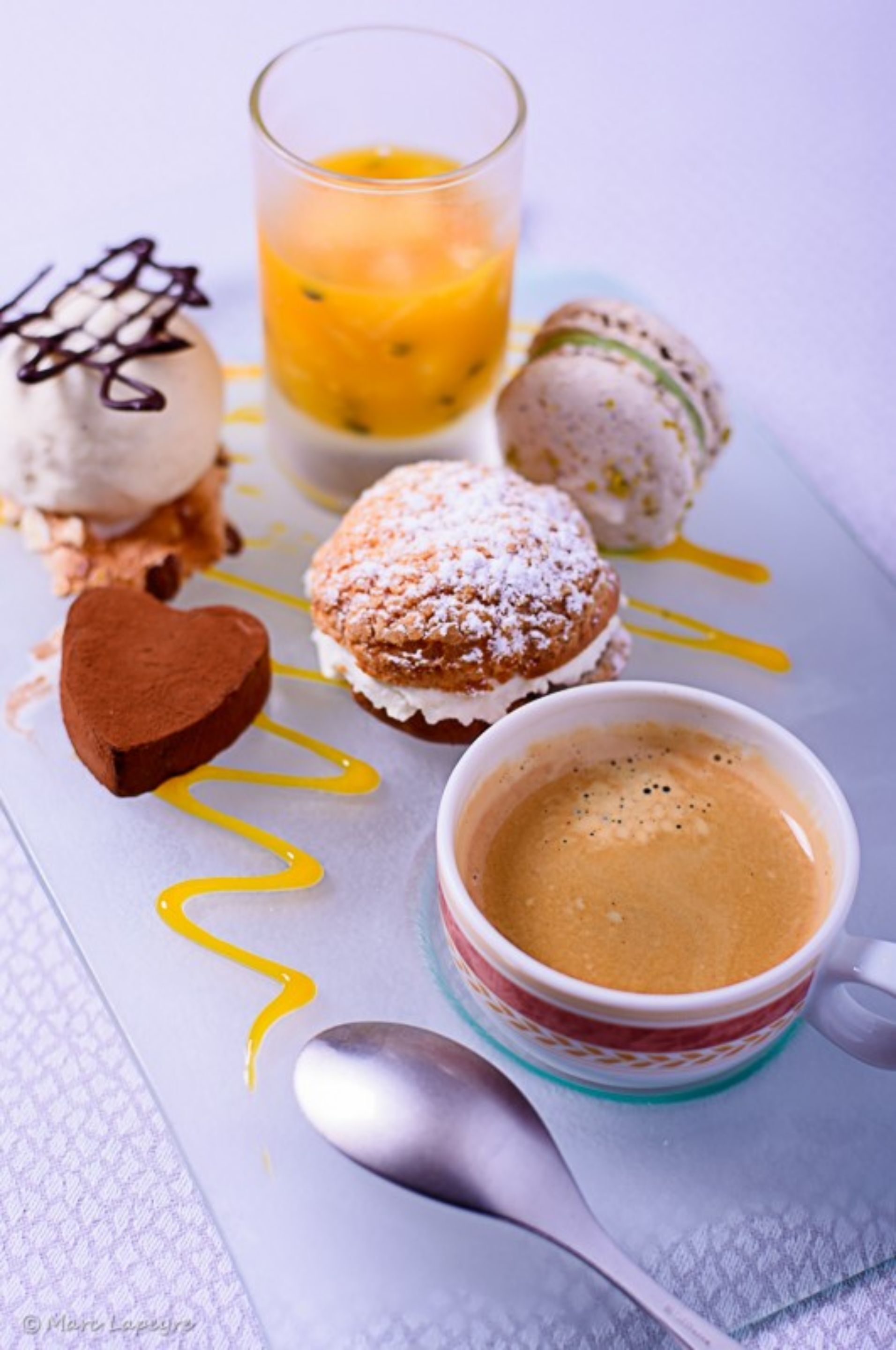A dessert tray with various sweets, a glass of orange juice, and a cup of coffee.