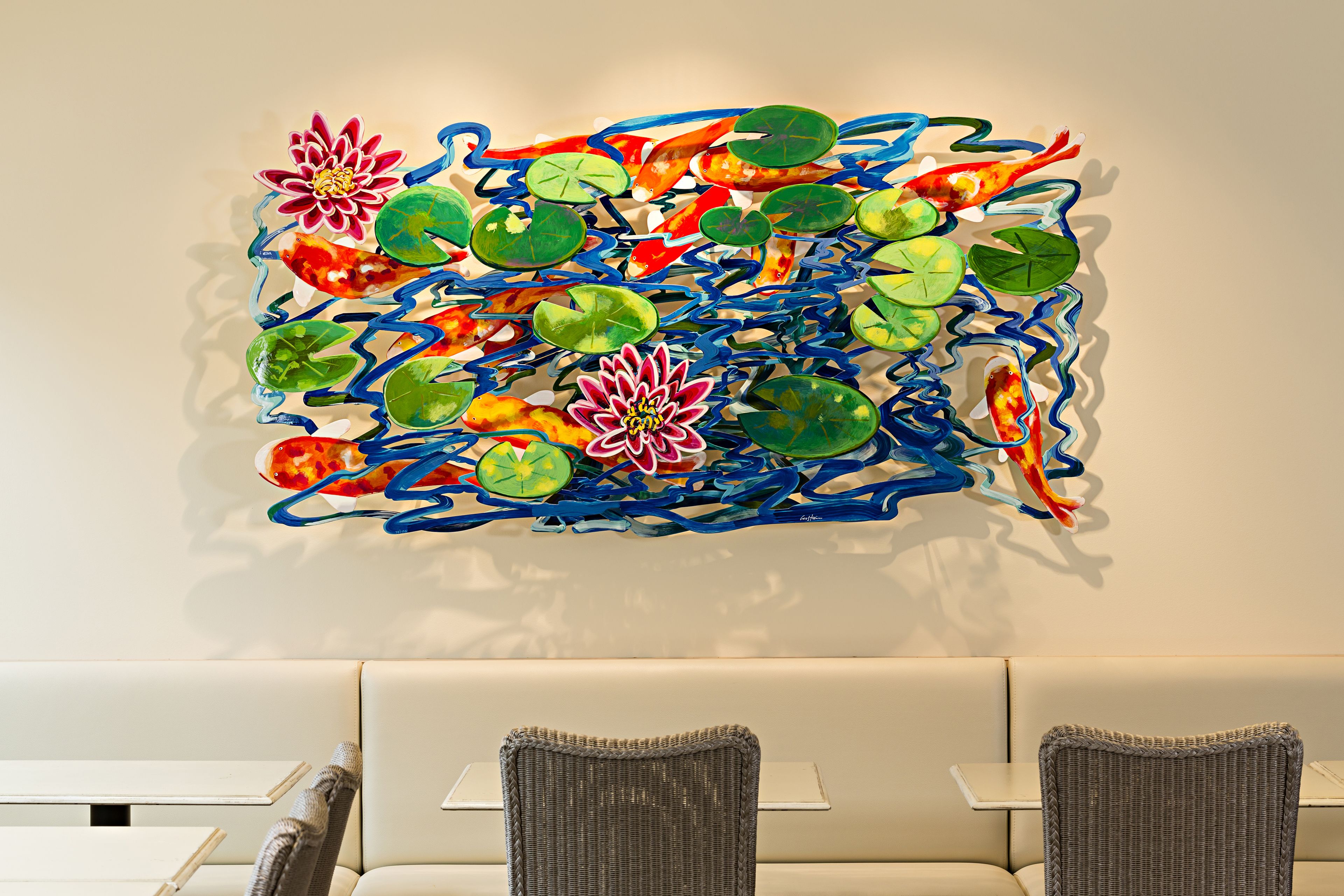 A modern interior with a colorful abstract wall art, a white sofa, and two wicker chairs.