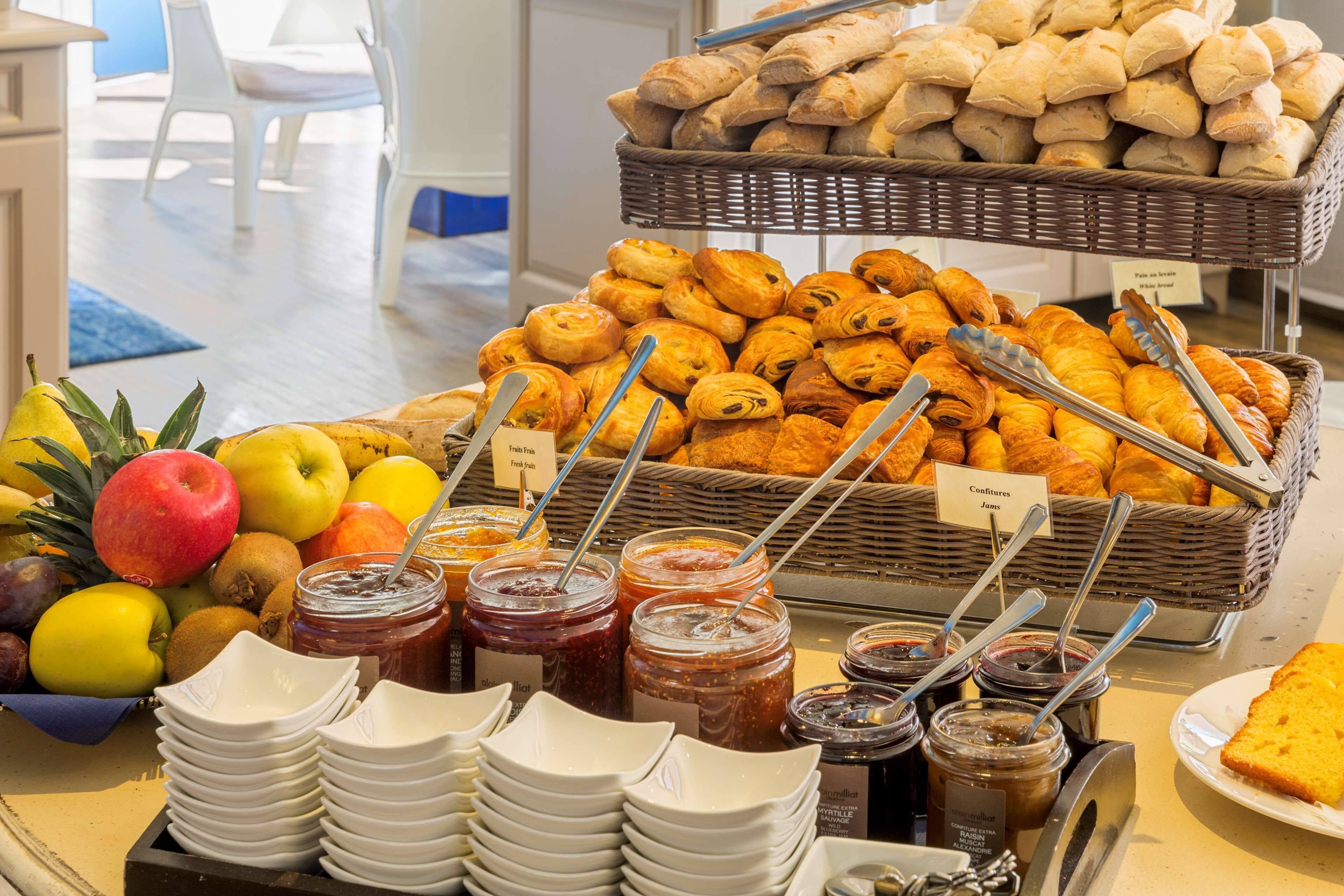 A buffet with various pastries, fruits, and condiments.