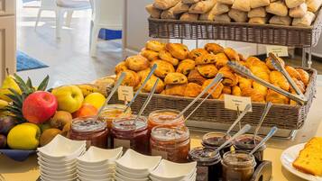 A buffet with various pastries, fruits, and condiments.