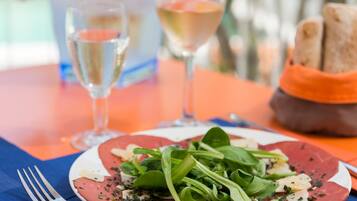 A plate of food with a fork and two glasses of white wine on a table.