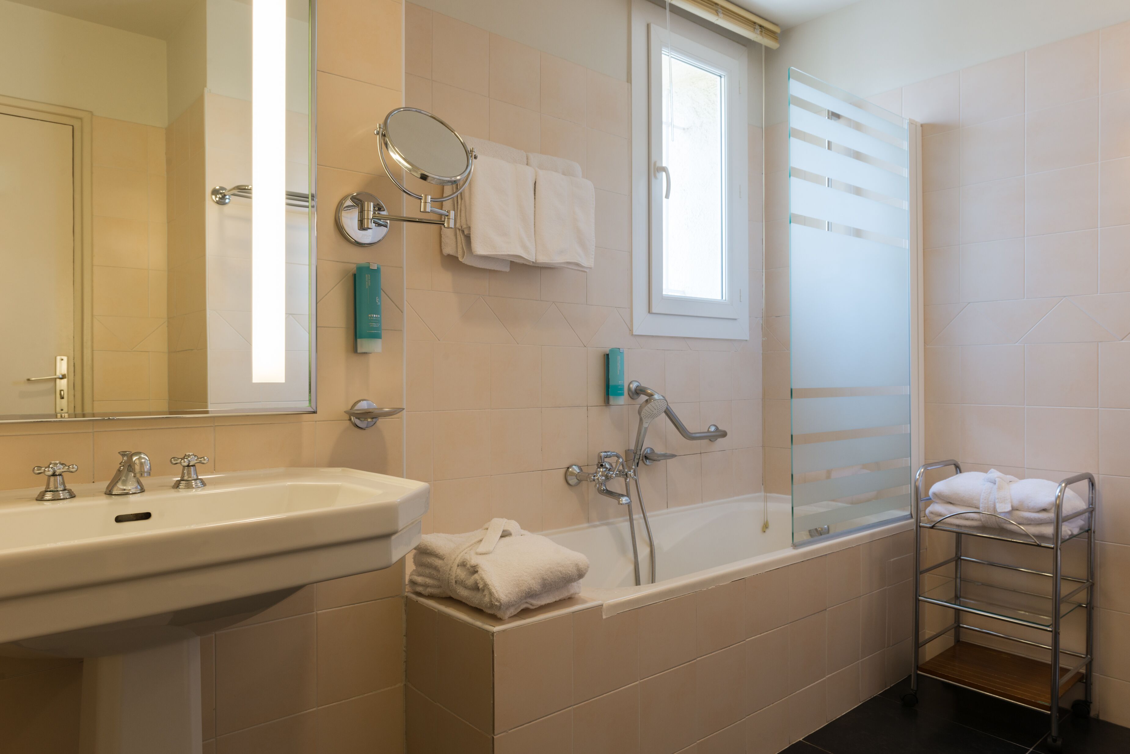 A bathroom with a sink, mirror, towel rack, and bathtub.