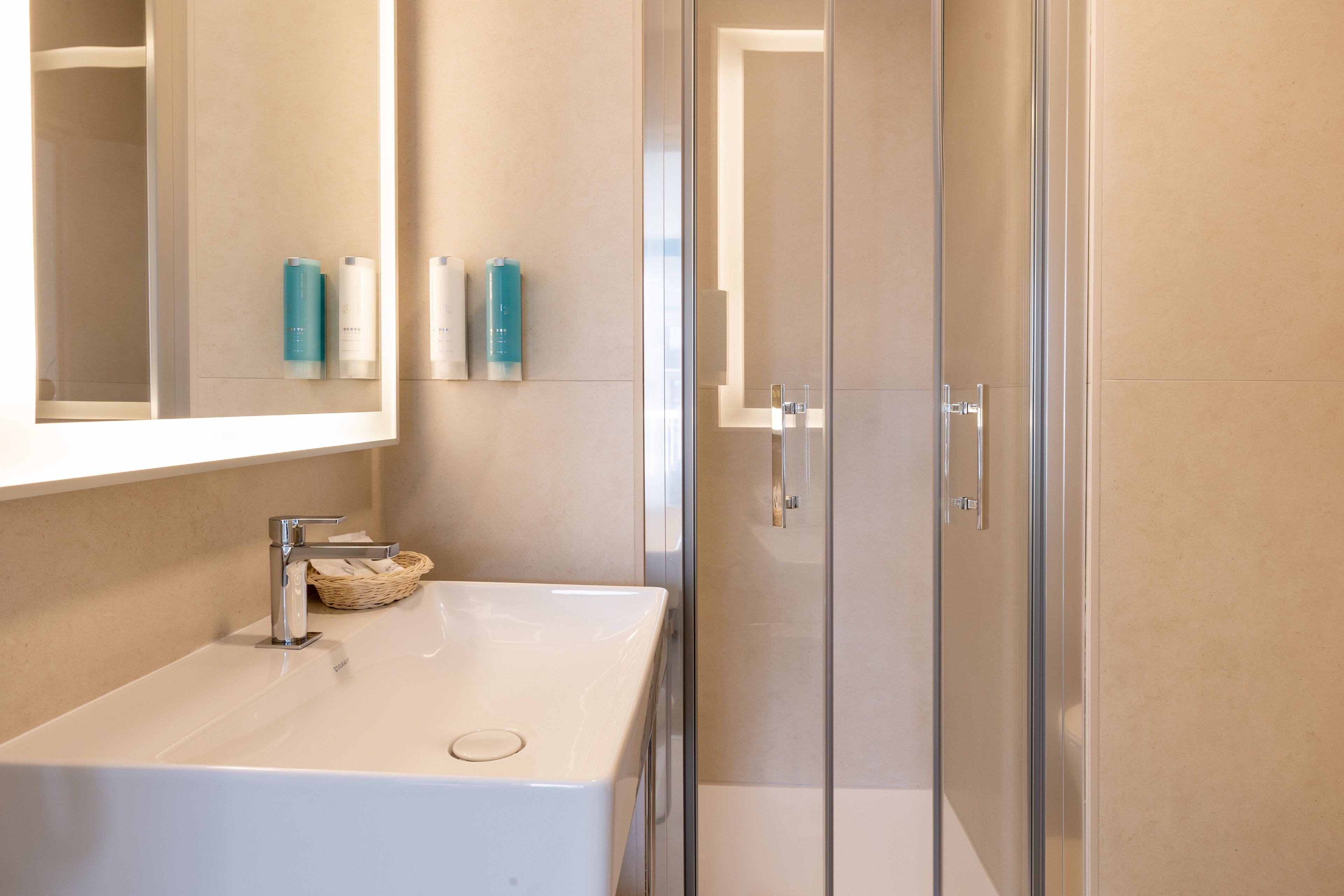 Ein modernes Badezimmer mit einem weißen Waschbecken, einem Spiegel und einer Duschkabine aus Glas.