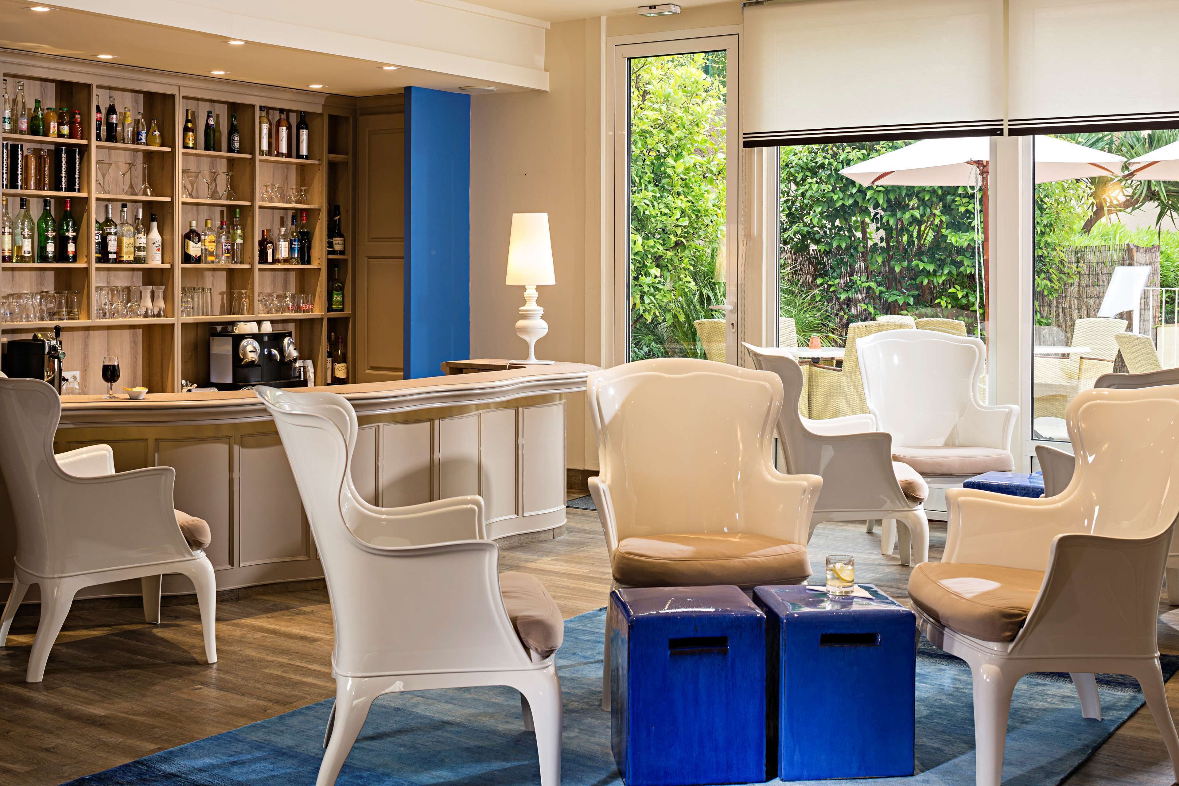 Un coin bar avec des chaises blanches, une table bleue et une étagère à bouteilles.