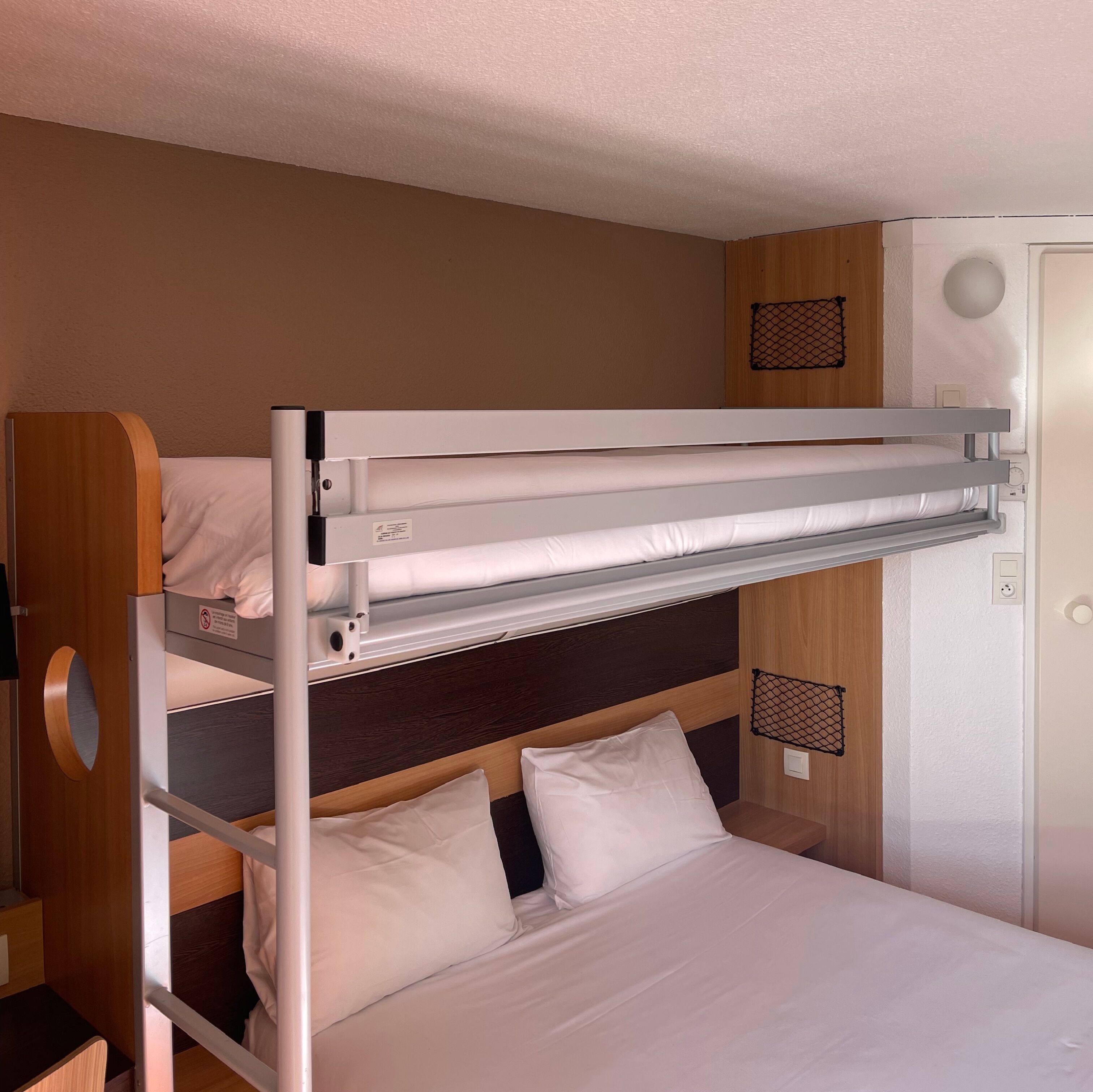 A bunk bed with a headboard, a bedside table, and a wall-mounted shelf.