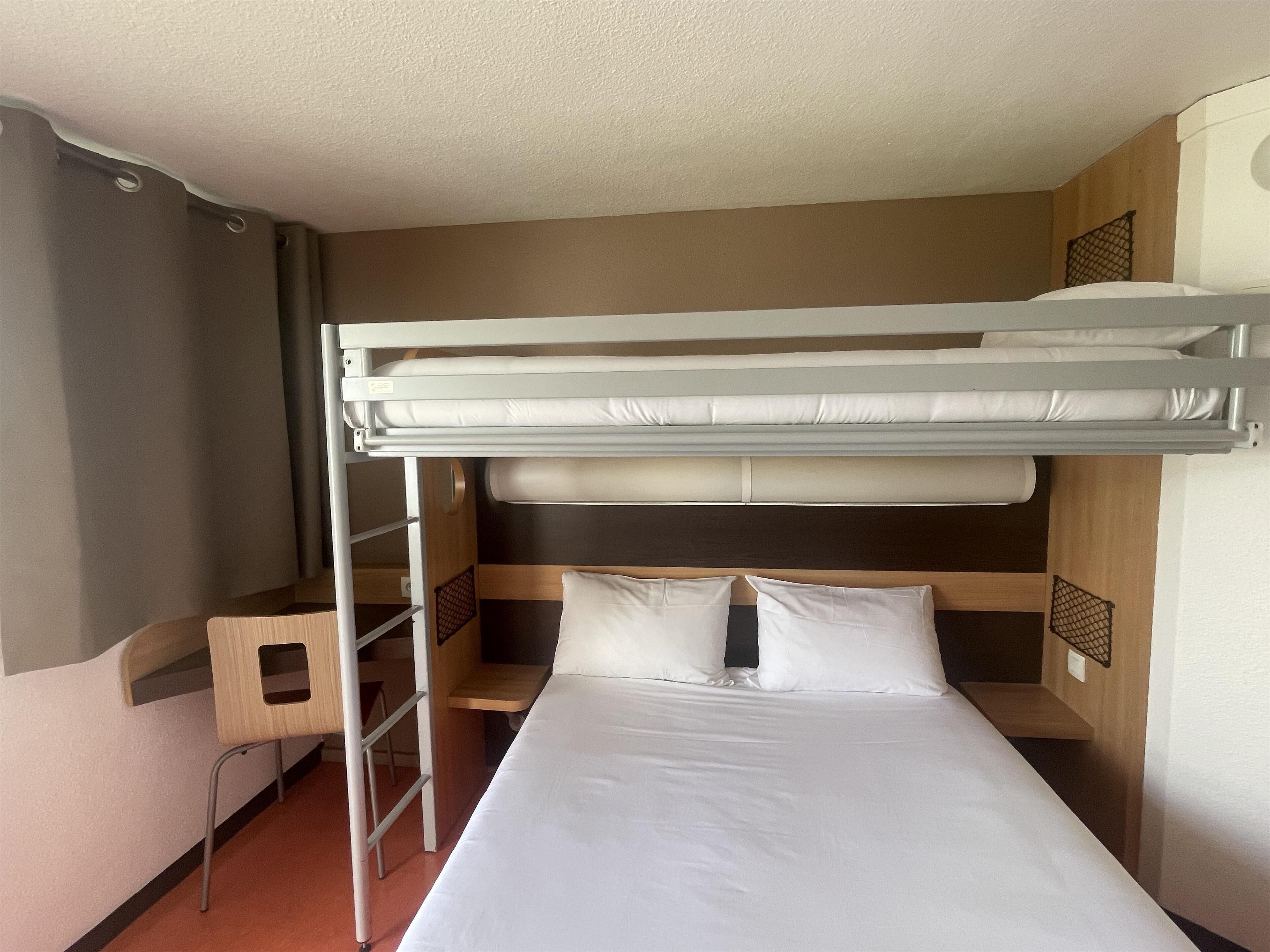 A bunk bed with a ladder, a small desk, and a shelf.