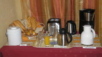 A breakfast setup with a toaster, coffee maker, and a tray with bread and beverages.