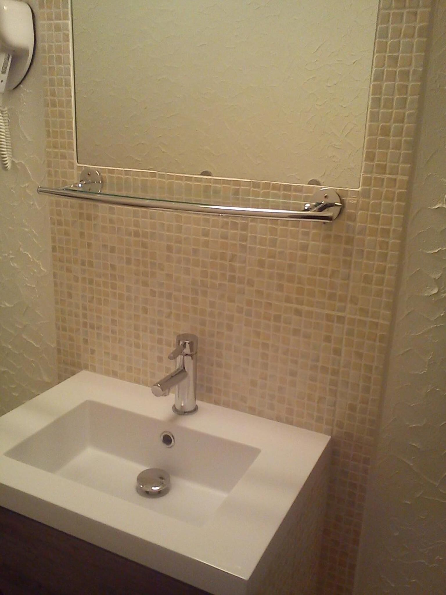 Une salle de bain avec un lavabo blanc, un miroir au-dessus et un porte-serviettes.