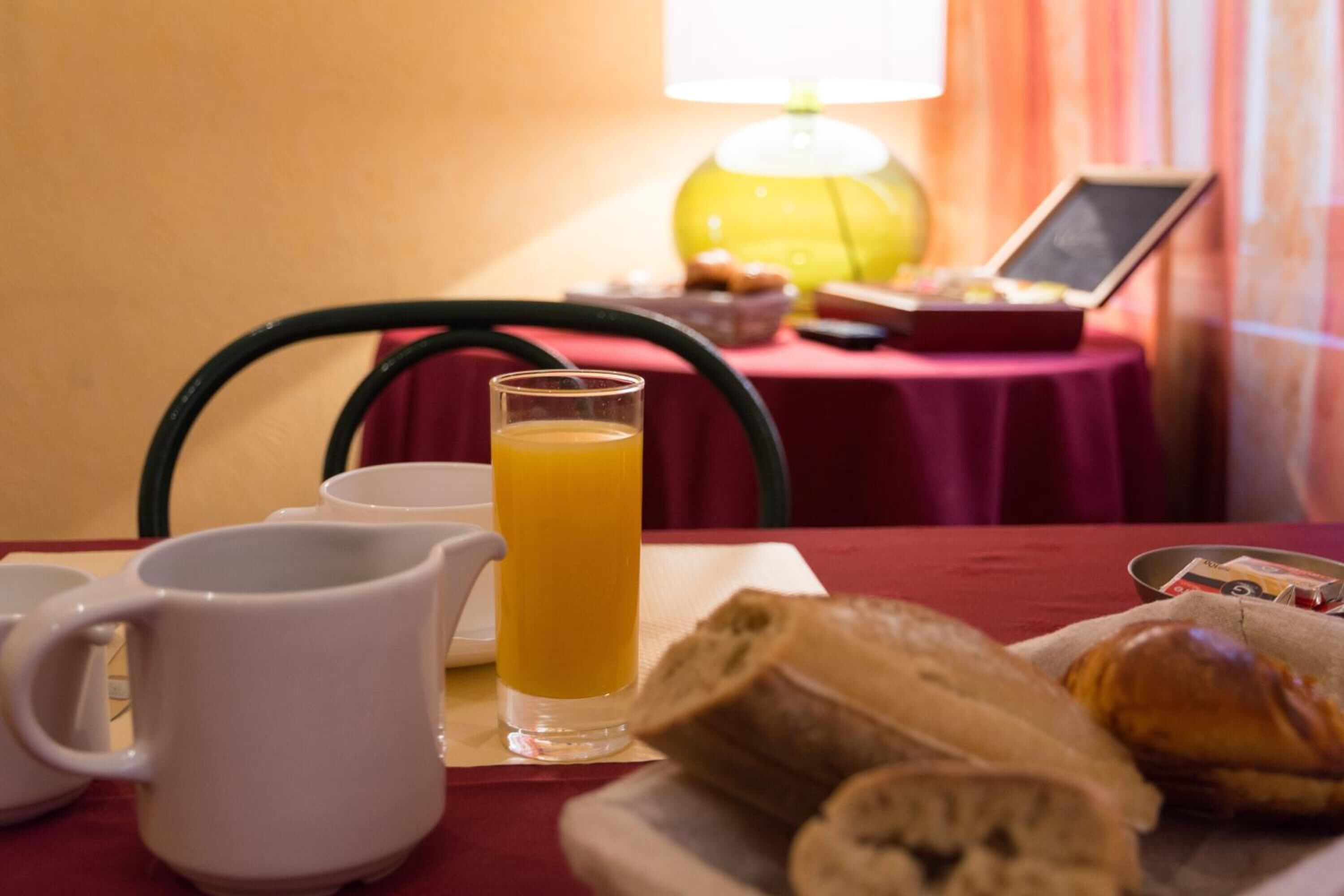 Een ontbijttafel met een glas sinaasappelsap, een witte mok en een bord croissants.