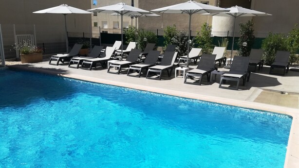 Une piscine avec des chaises longues et des parasols.