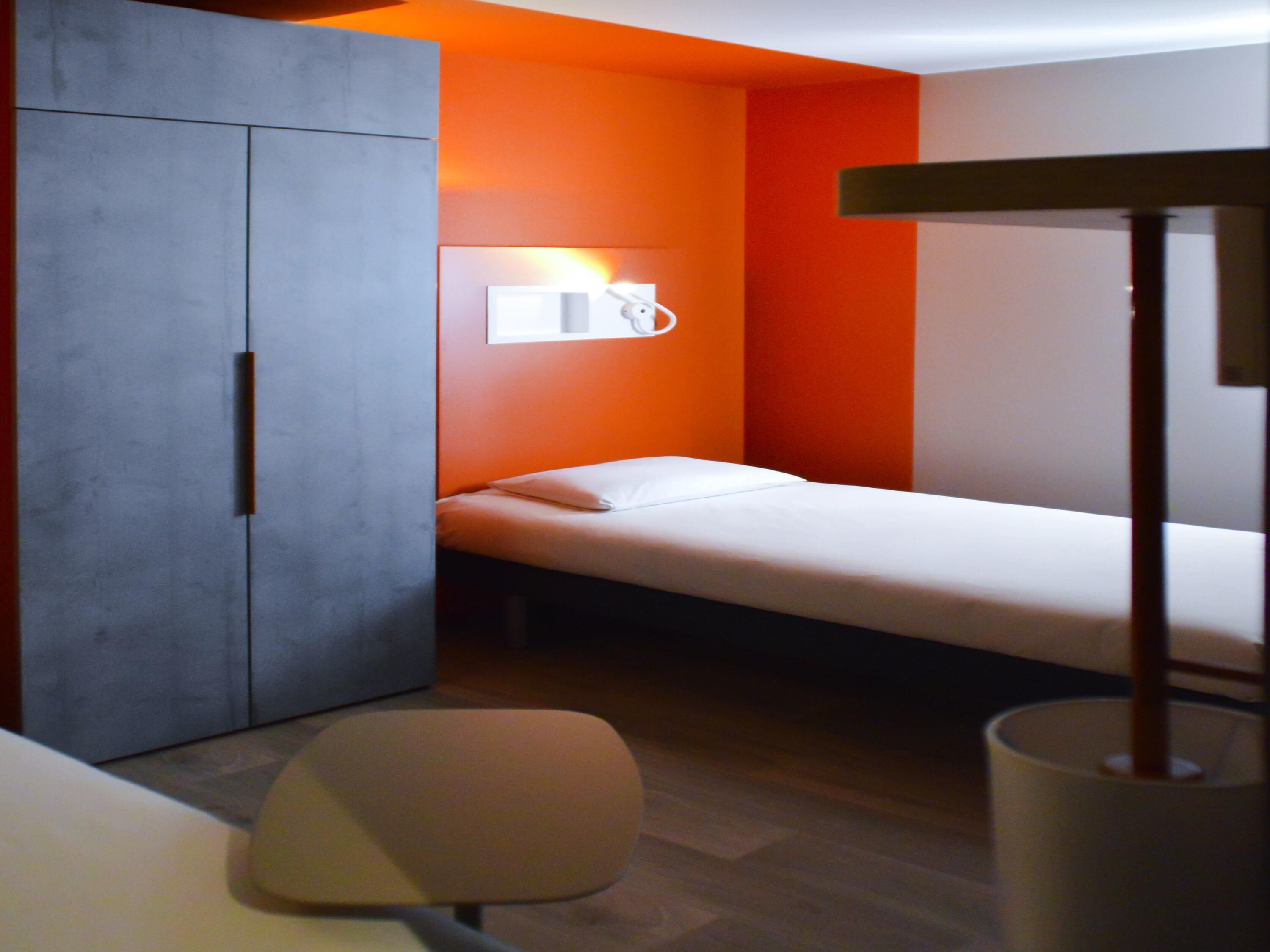 Una habitación pequeña y funcional con cama, armario y escritorio.