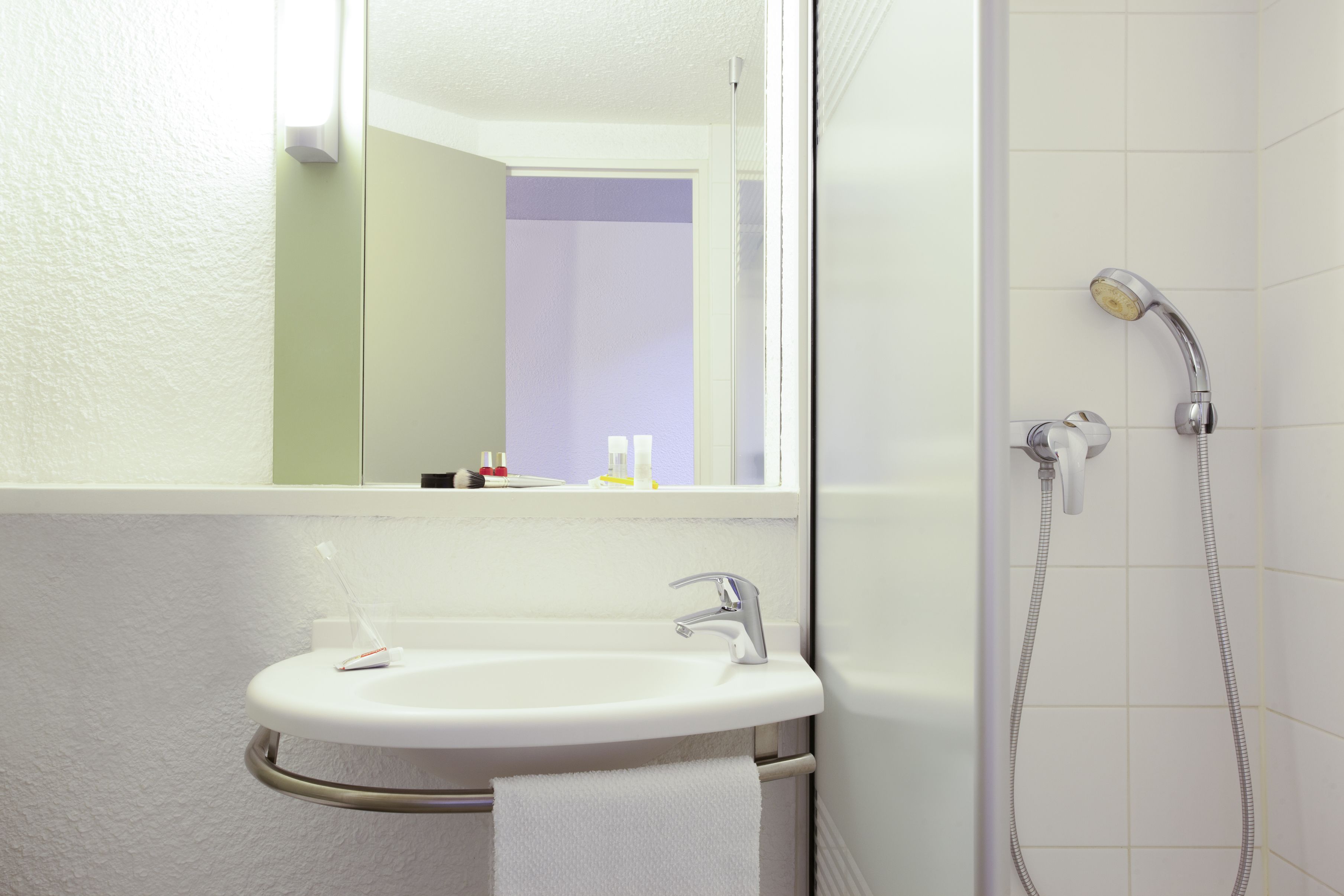 A bathroom with a white sink, a mirror, and a shower.