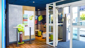 Un intérieur moderne avec un plancher en bois, une porte d’entrée en verre et une enseigne faisant la promotion de « Planet 21 », en mettant l’accent sur les thèmes de la nature, de l’innovation et de l’emploi local.