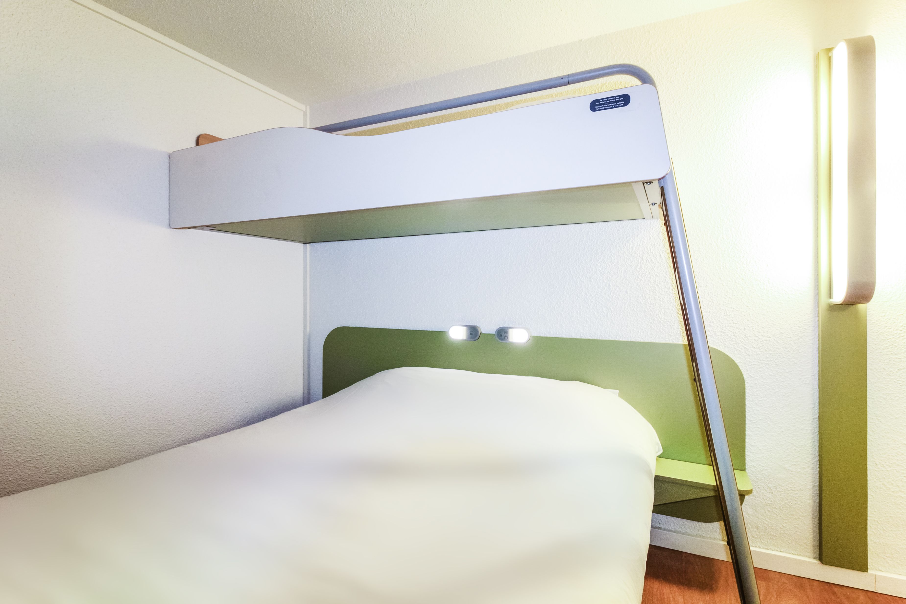 Ein Stockbett mit einem grünen Kopfteil und einer weißen Matratze.