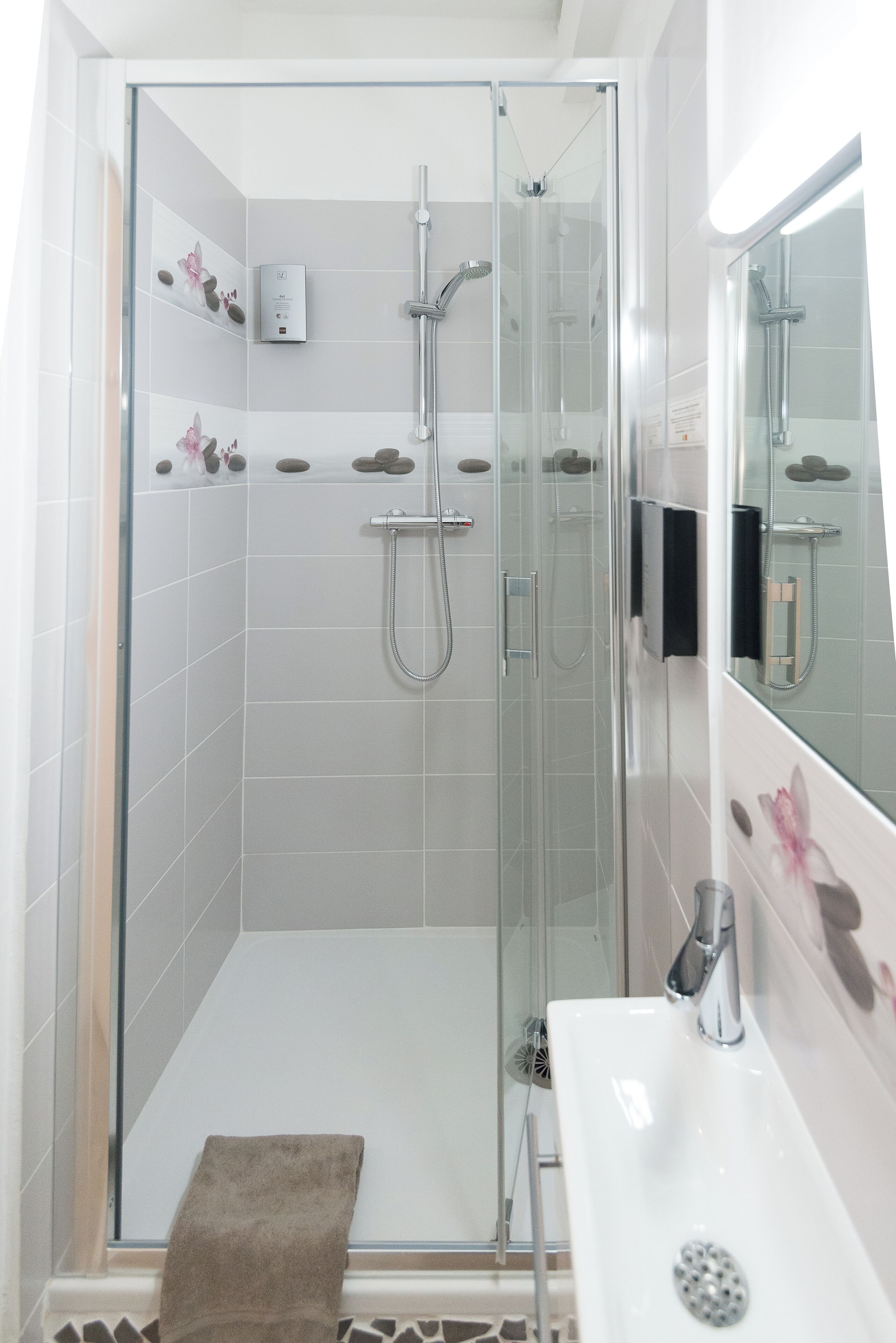 A modern bathroom with a glass-enclosed shower, a white sink, and a mirror.