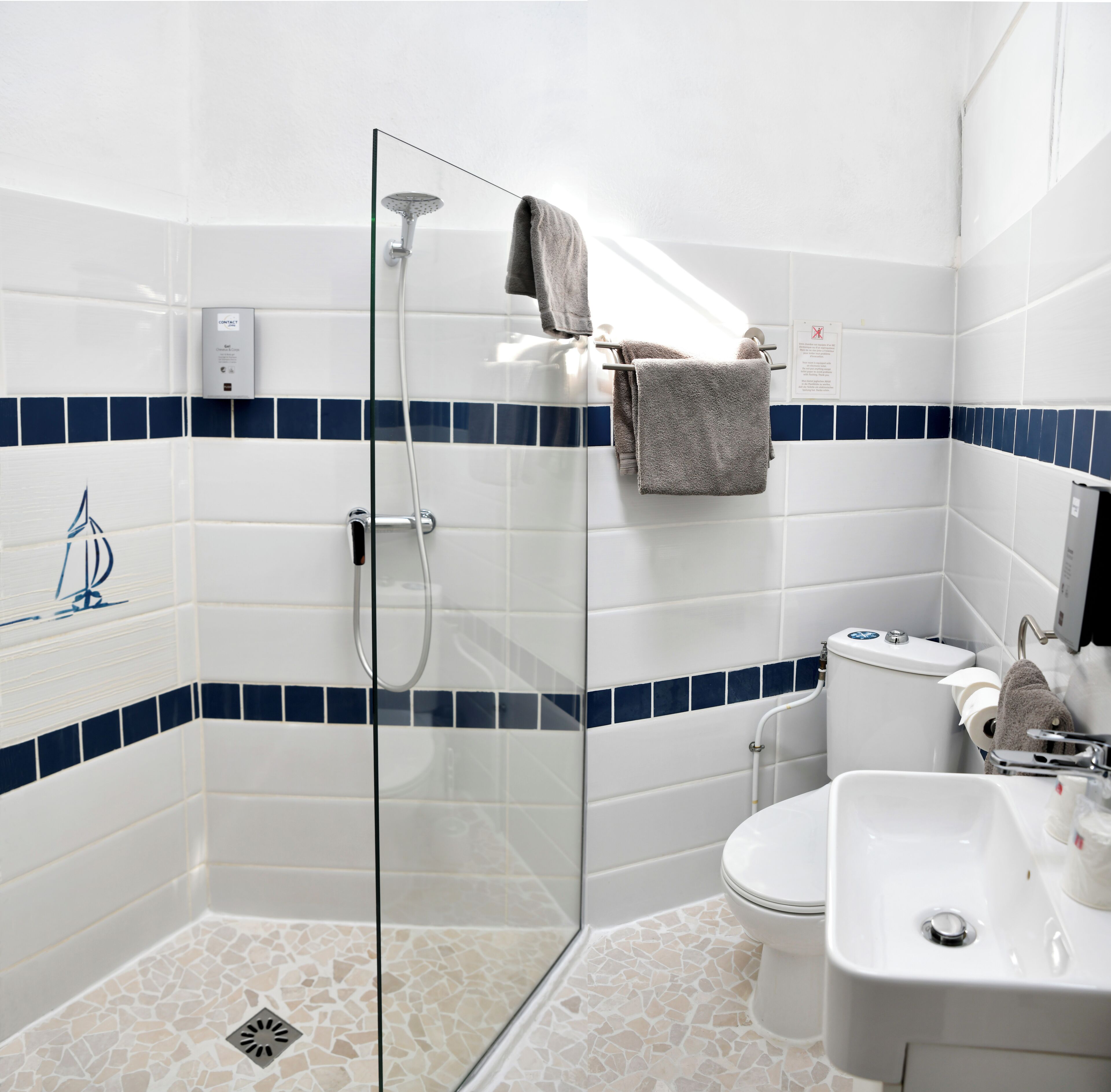 A modern bathroom with a glass shower enclosure, a white sink, and a toilet.