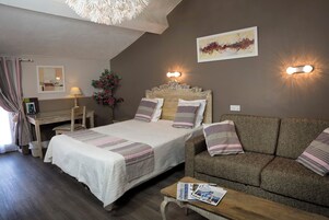 Un dormitorio con cama, sofá, escritorio y lámpara.