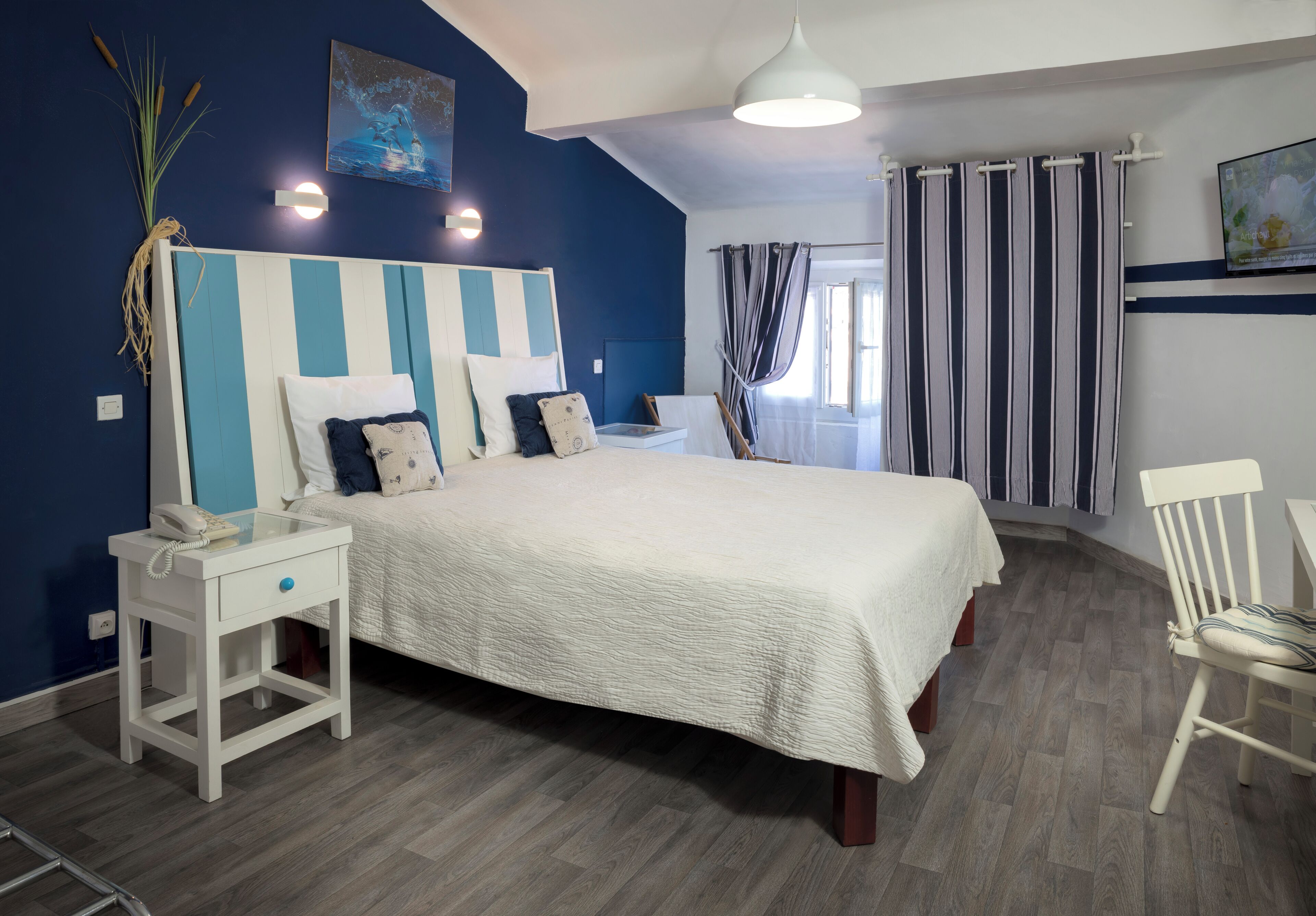 Een slaapkamer met een bed, nachtkastje, lamp en gordijnen.