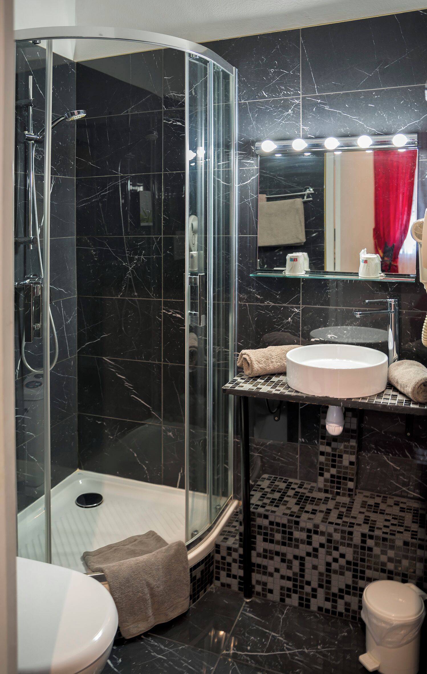 A modern bathroom with a glass-enclosed shower, a vanity with a sink, and a mirror with lights.