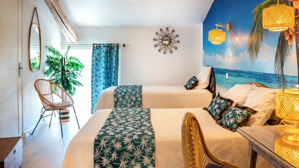 Una habitación con cama, una silla, una planta y un mural de playa.