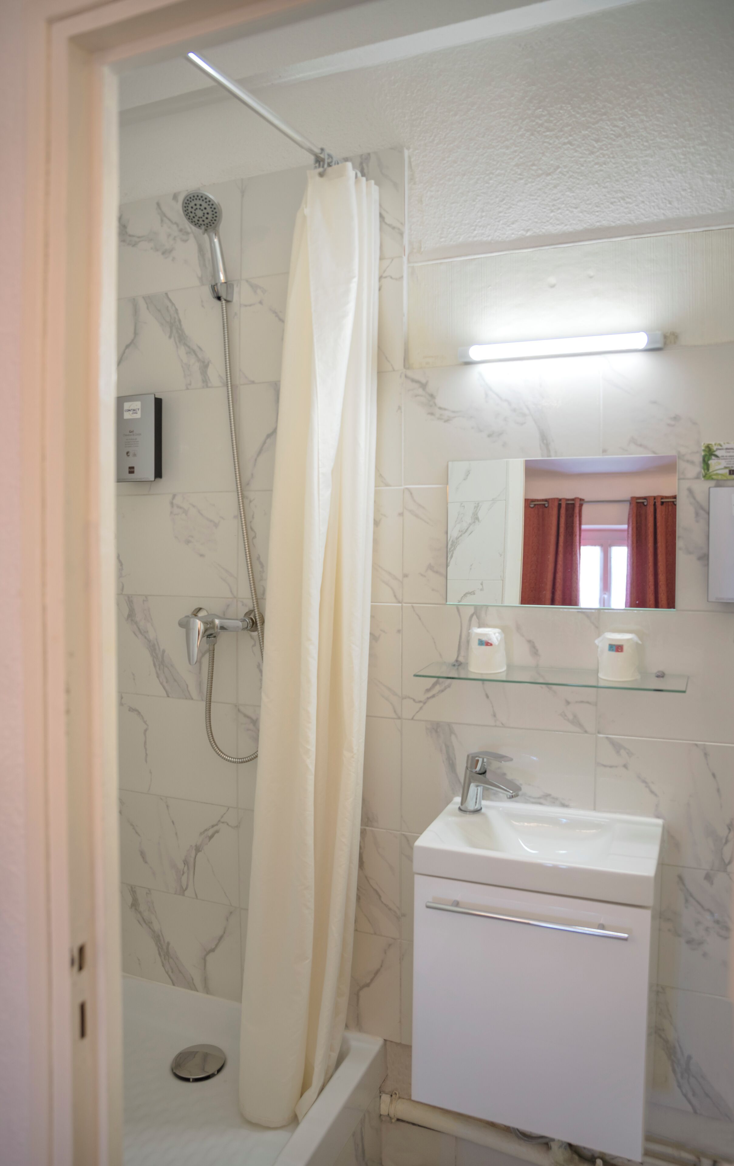 A bathroom with a shower, a sink, and a mirror.