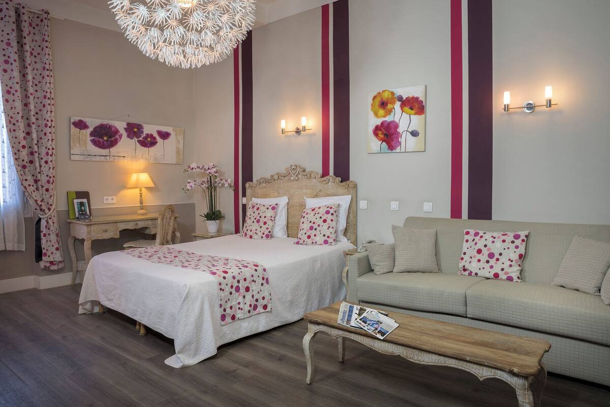 A bedroom with a bed, a bedside table, a lamp, a sofa, and a coffee table.
