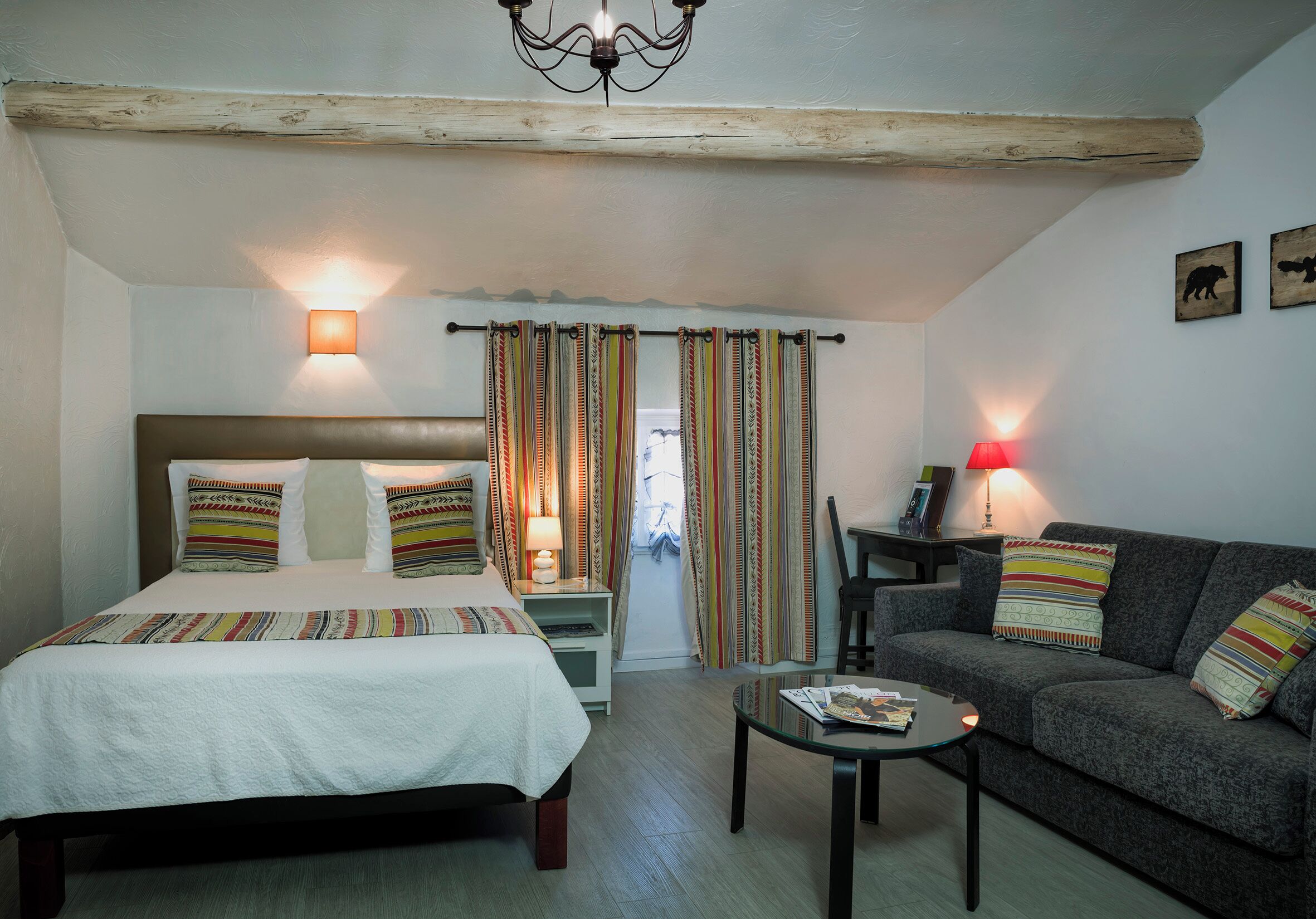 A bedroom with a bed, a sofa, a small table, and two bedside lamps.
