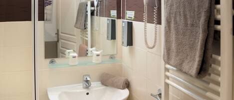 A modern bathroom with a sink, mirror, towel rack, and a hairdryer.