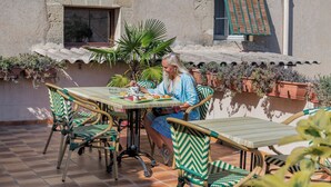 Un patio con una mesa y sillas, rodeado de macetas con plantas.