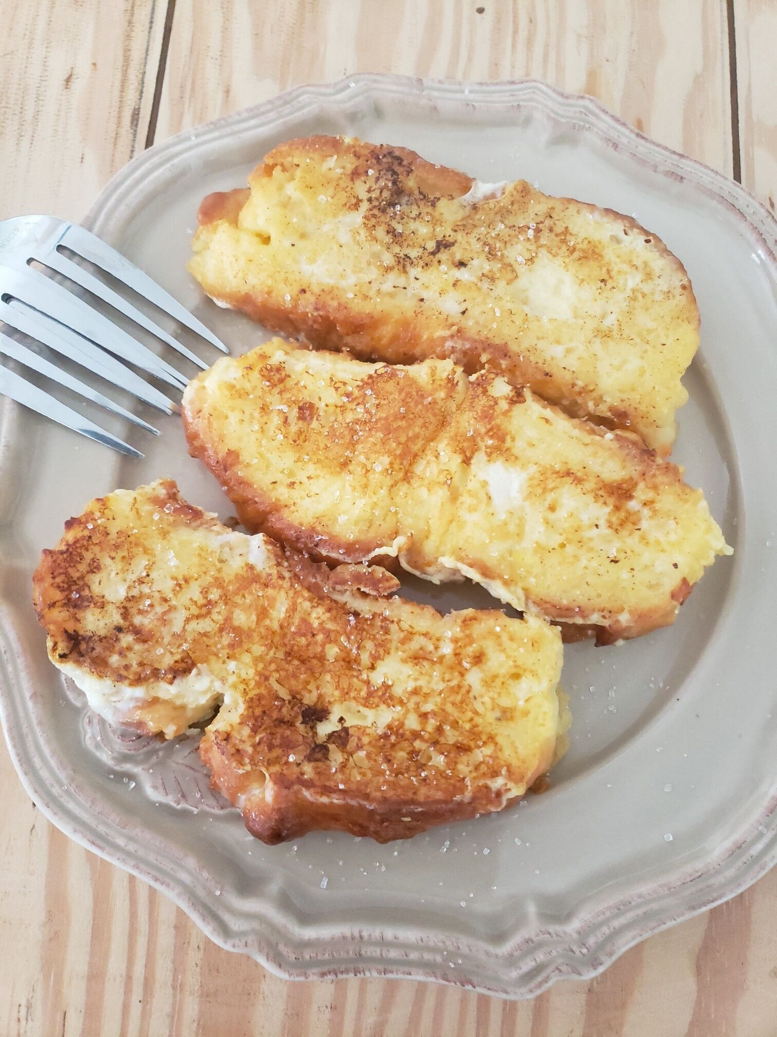 A plate with four pieces of breaded and fried food, possibly chicken or pork, on a ceramic plate with a fork beside it.