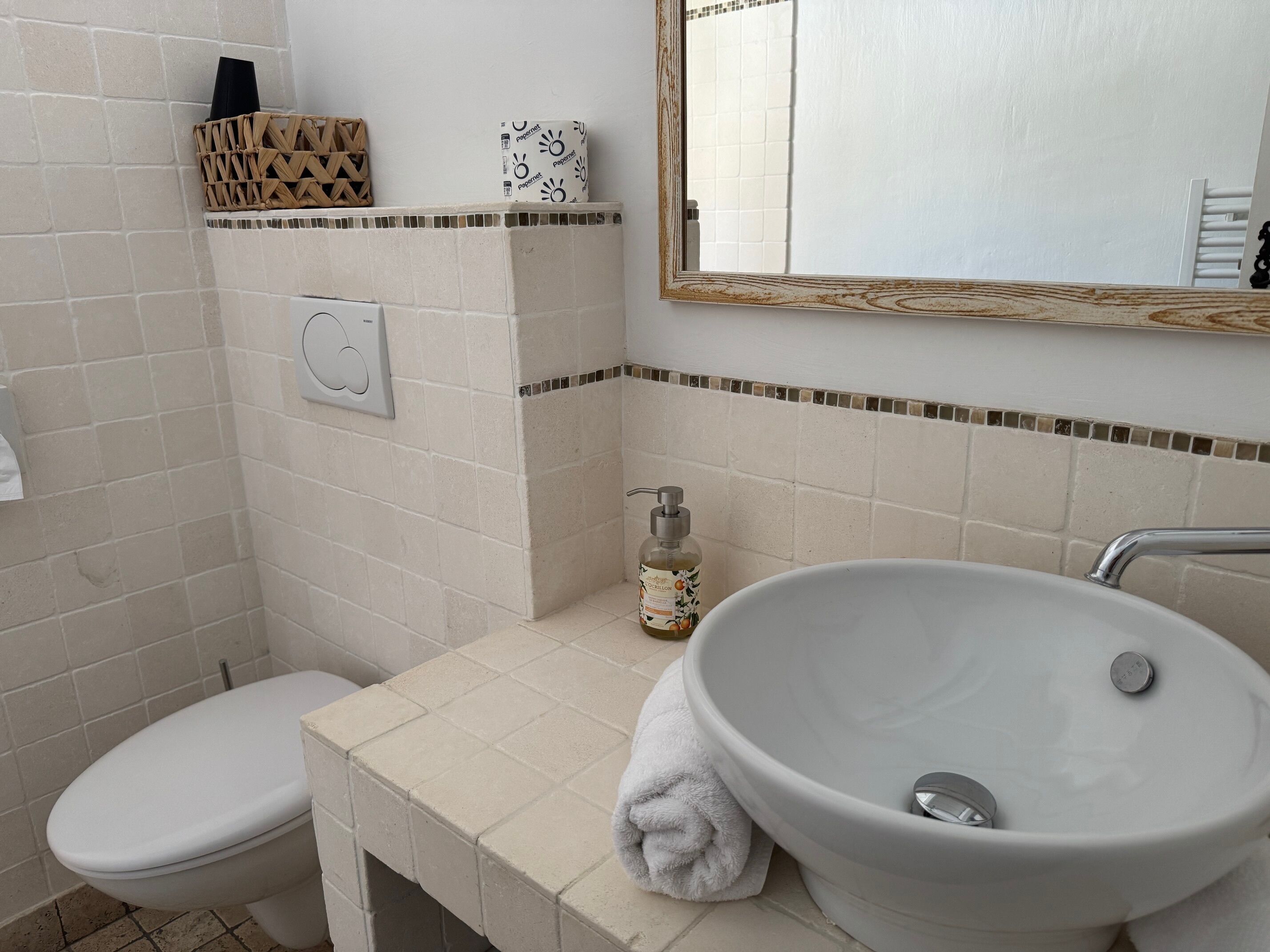 Un bagno con il water, un lavandino, uno specchio e un erogatore di sapone.