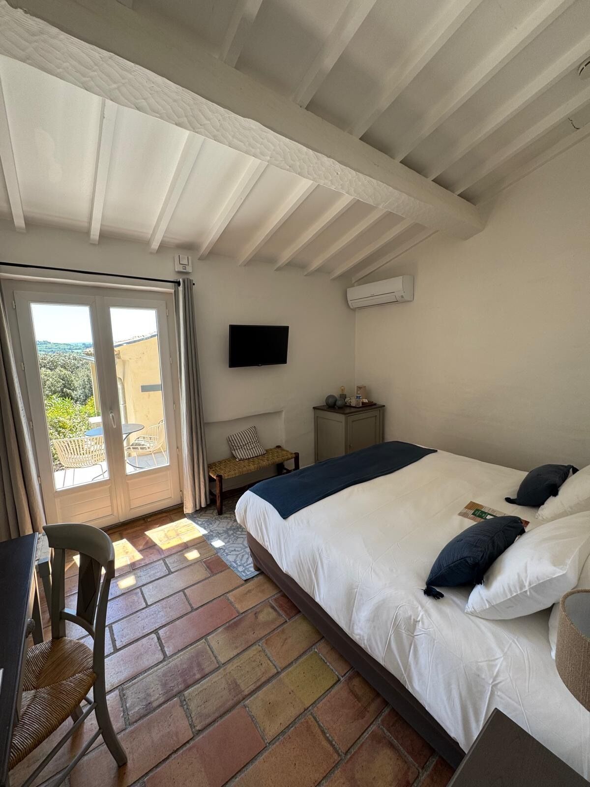 Un dormitorio con una cama, televisión, escritorio y silla.