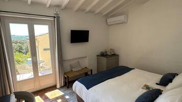 Un dormitorio con una cama, televisión, escritorio y silla.