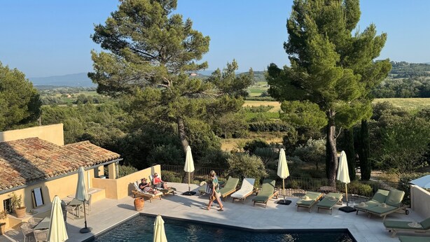 A pool area with lounge chairs and umbrellas, surrounded by trees and a view of the countryside. - Le Mas de Garrigon - Boutique Hôtel & Spa (Roussillon)