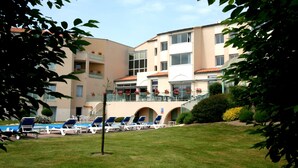 Un hotel con piscina, sillones de descanso y jardín.