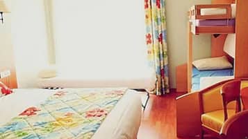 Ein Hotelzimmer mit Bett, Stuhl, Schreibtisch und einem fenster mit Vorhängen.