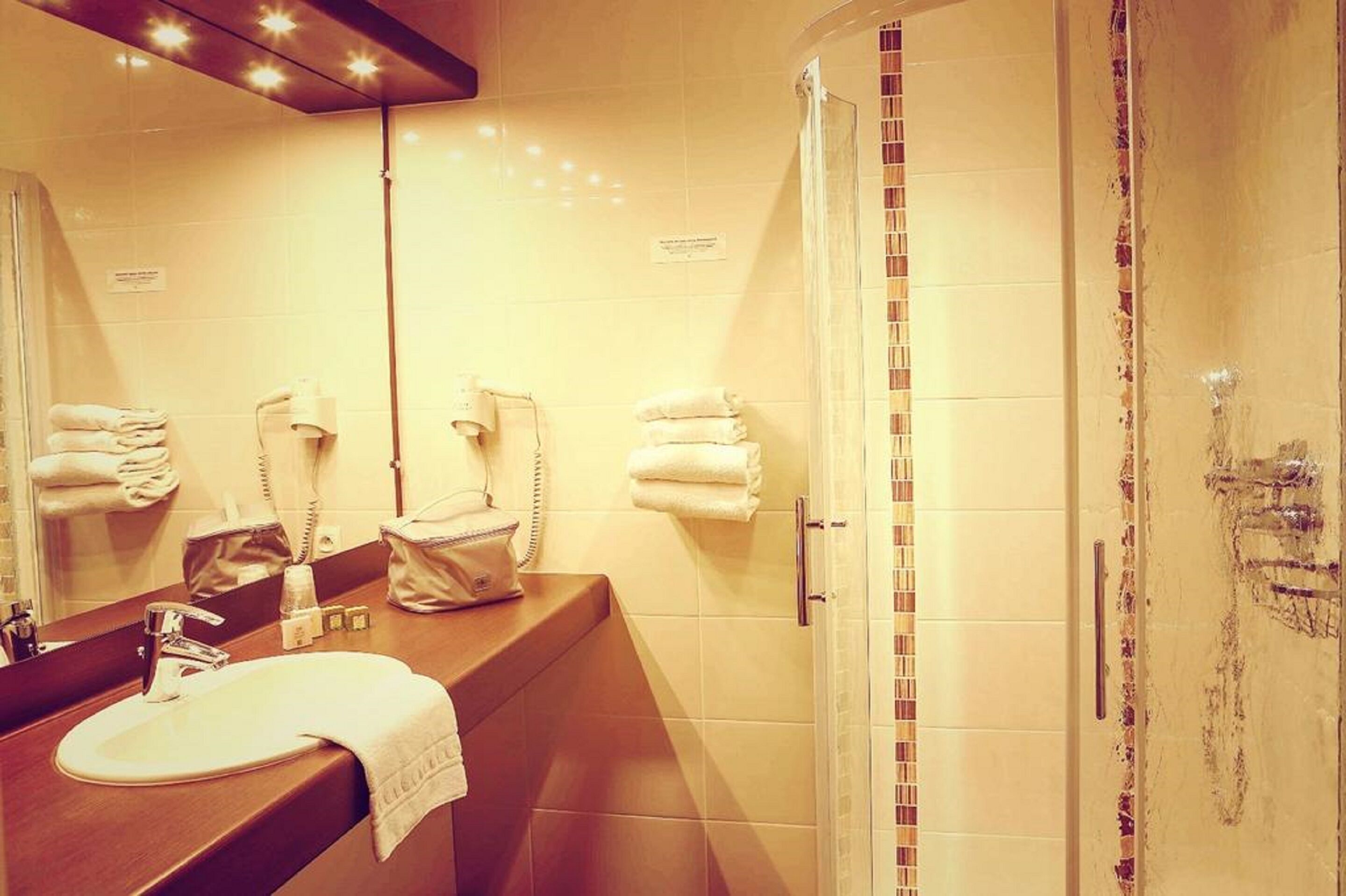 A bathroom with a sink, mirror, and a shower with a glass door.